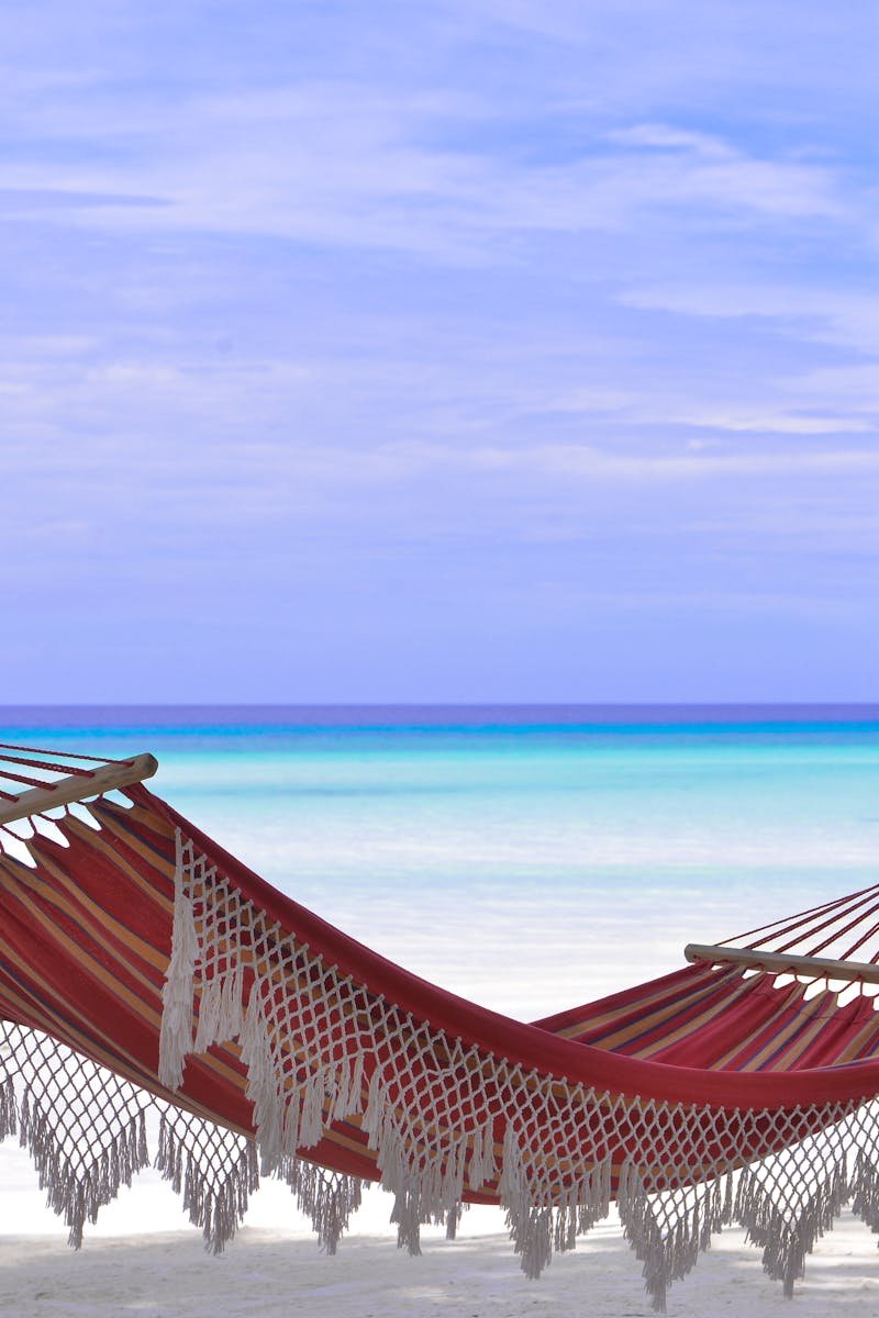 Idyllic beach hammock between coconut trees with azure blue waters.