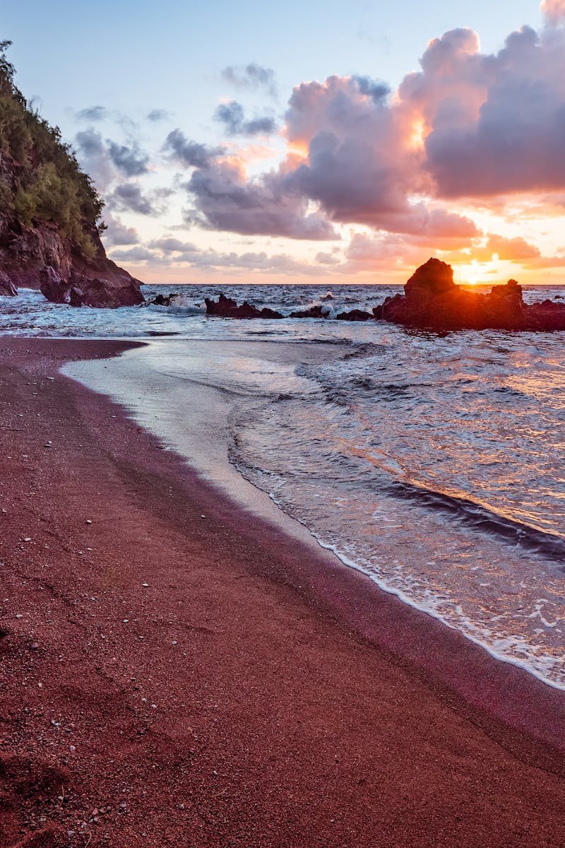 Discover the stunning sunrise over Kaihalulu Beach's unique red sands in Hana, Hawaii.